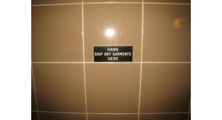 The sign says hang drip dry garments here, but there is no hook.